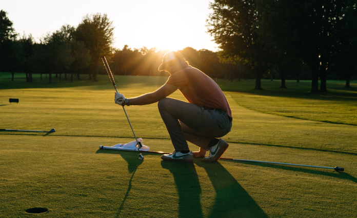 man in golf course during sunset
